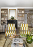 Salón con sofá beige, sillones tapizados en mostaza y blanco, cojines decorativos y cuadro abstracto en vivienda familiar de Algorta