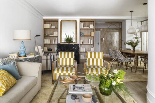 Salón con sofá beige, sillones tapizados en mostaza y blanco, cojines decorativos y cuadro abstracto en vivienda familiar de Algorta