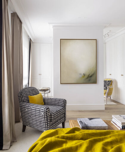 Suite principal con butaca de cuadros, gran cuadro abstracto y vestidor integrado en reforma de vivienda familiar en Algorta, Getxo